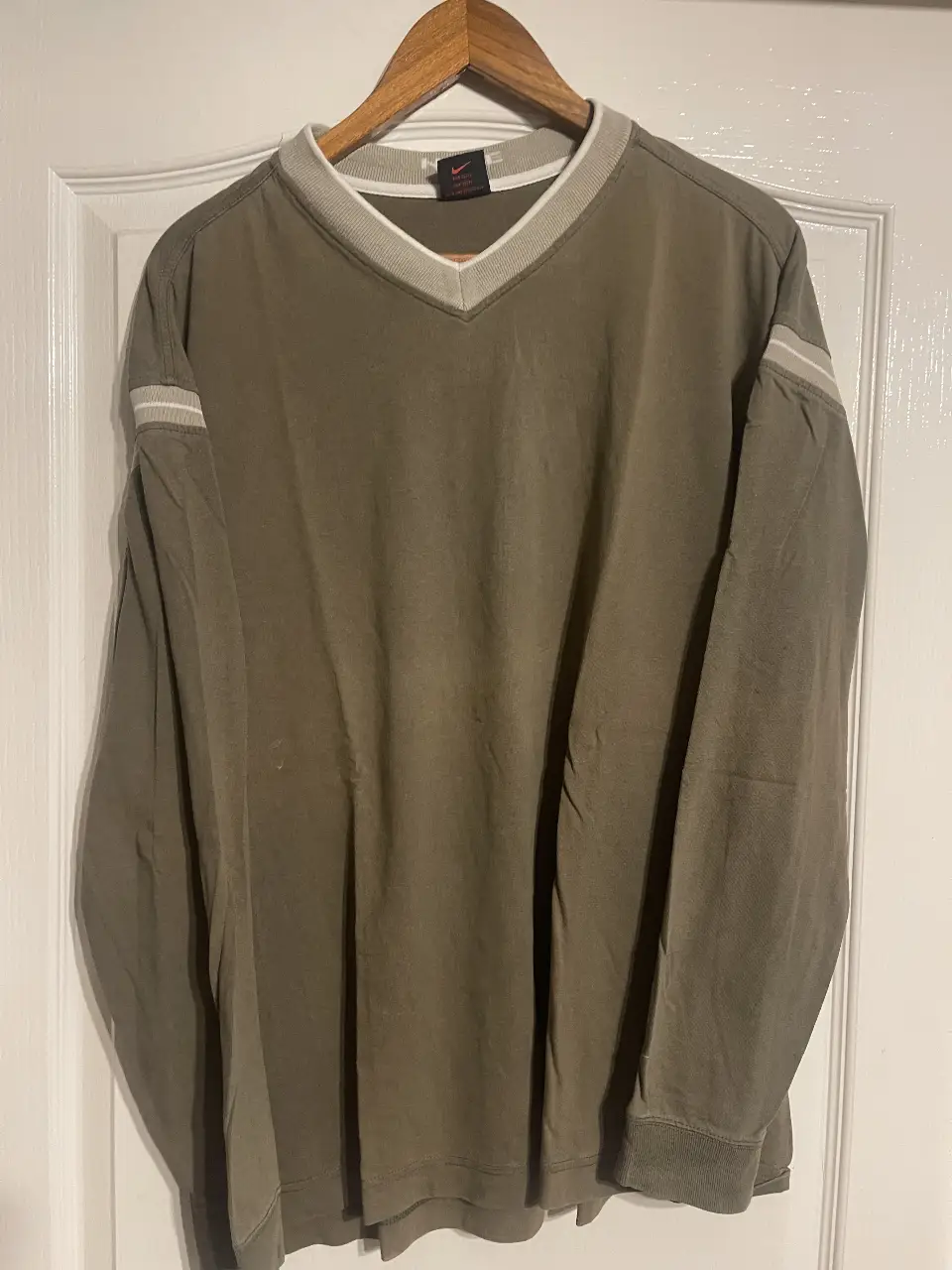 Buzo manga larga con cuello en V, color verde oscuro con detalles en blanco en mangas y cuello. Ideal para un look casual y cómodo.