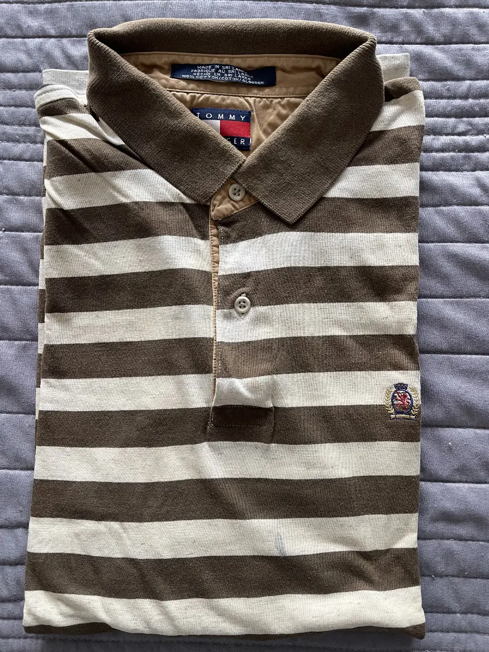 Remera polo a rayas horizontales marrones y blancas, con cuello marrón y detalles en el mismo color. Logo bordado en el pecho. Ideal para un look casual y preppy.