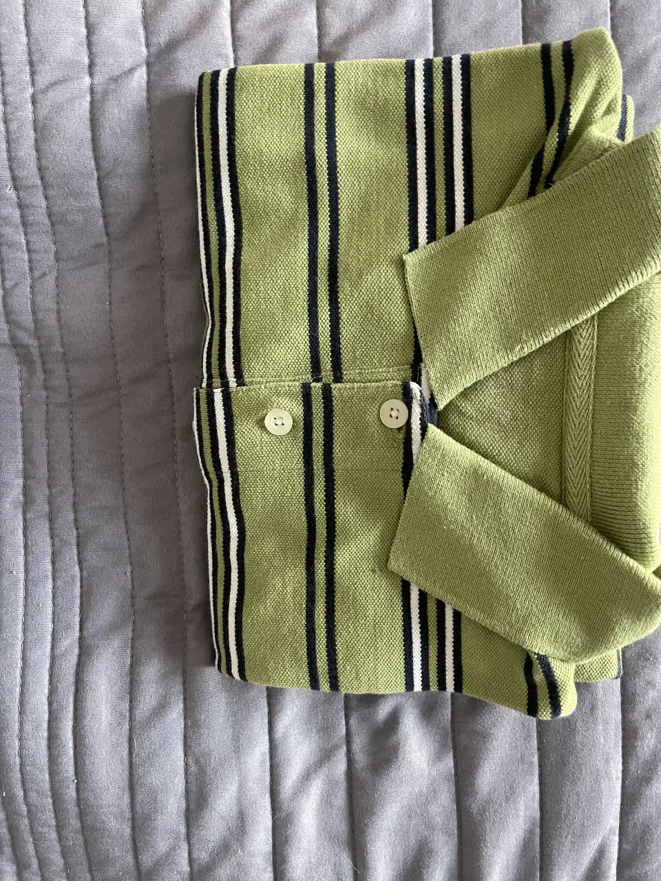 Camisa polo a rayas verdes con detalles en blanco y negro. Ideal para un look casual y fresco.