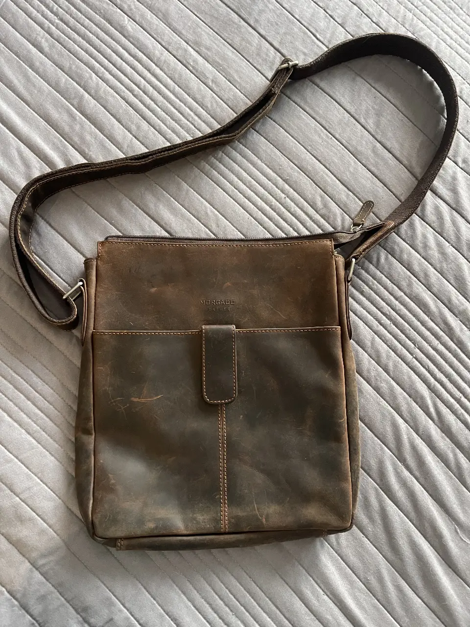 Bandolera de cuero marrón con solapa y cierre. Ideal para uso diario, con un diseño clásico y resistente.