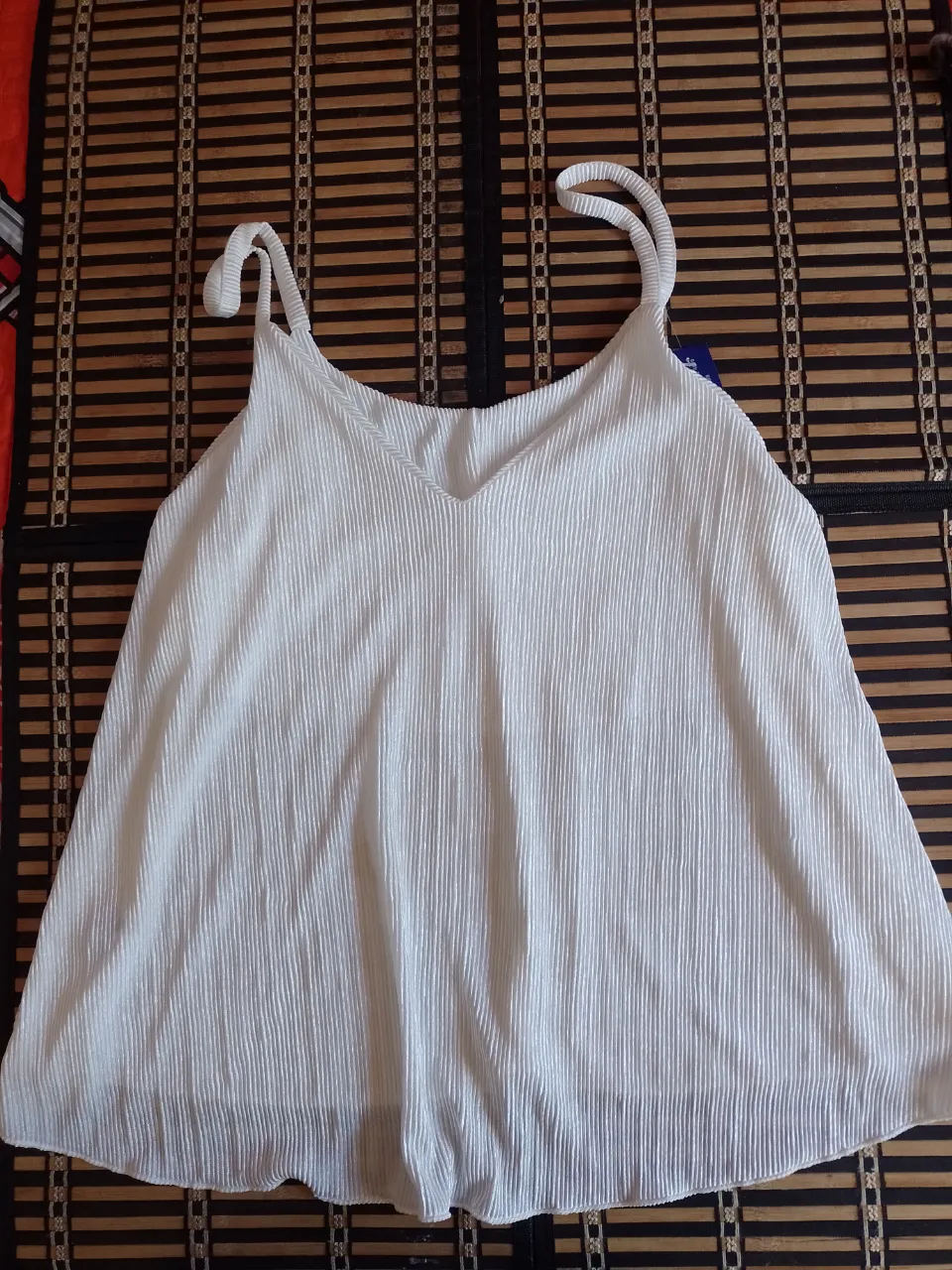 Musculosa blanca con breteles finos y escote en V. Posee un tejido acanalado.