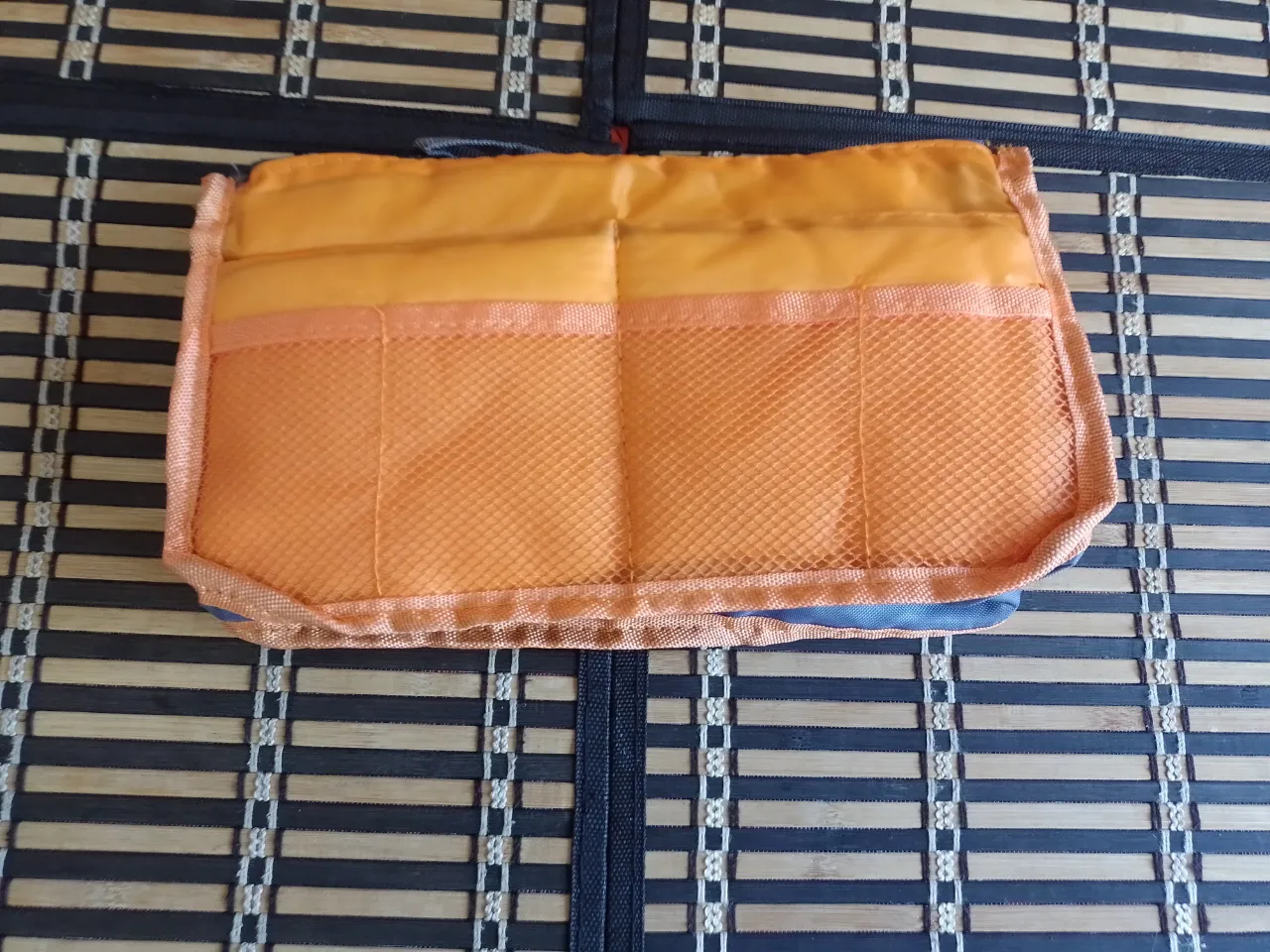 Organizador de cartera naranja con múltiples compartimentos y bolsillos de red.