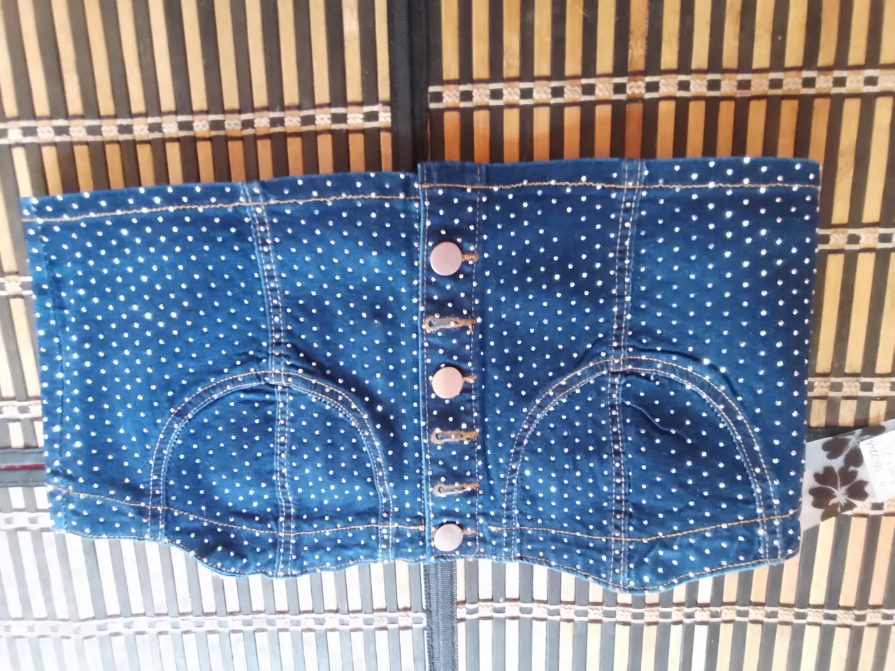 Top de jean azul con estampa de lunares blancos. Posee botones al frente y bolsillos falsos.