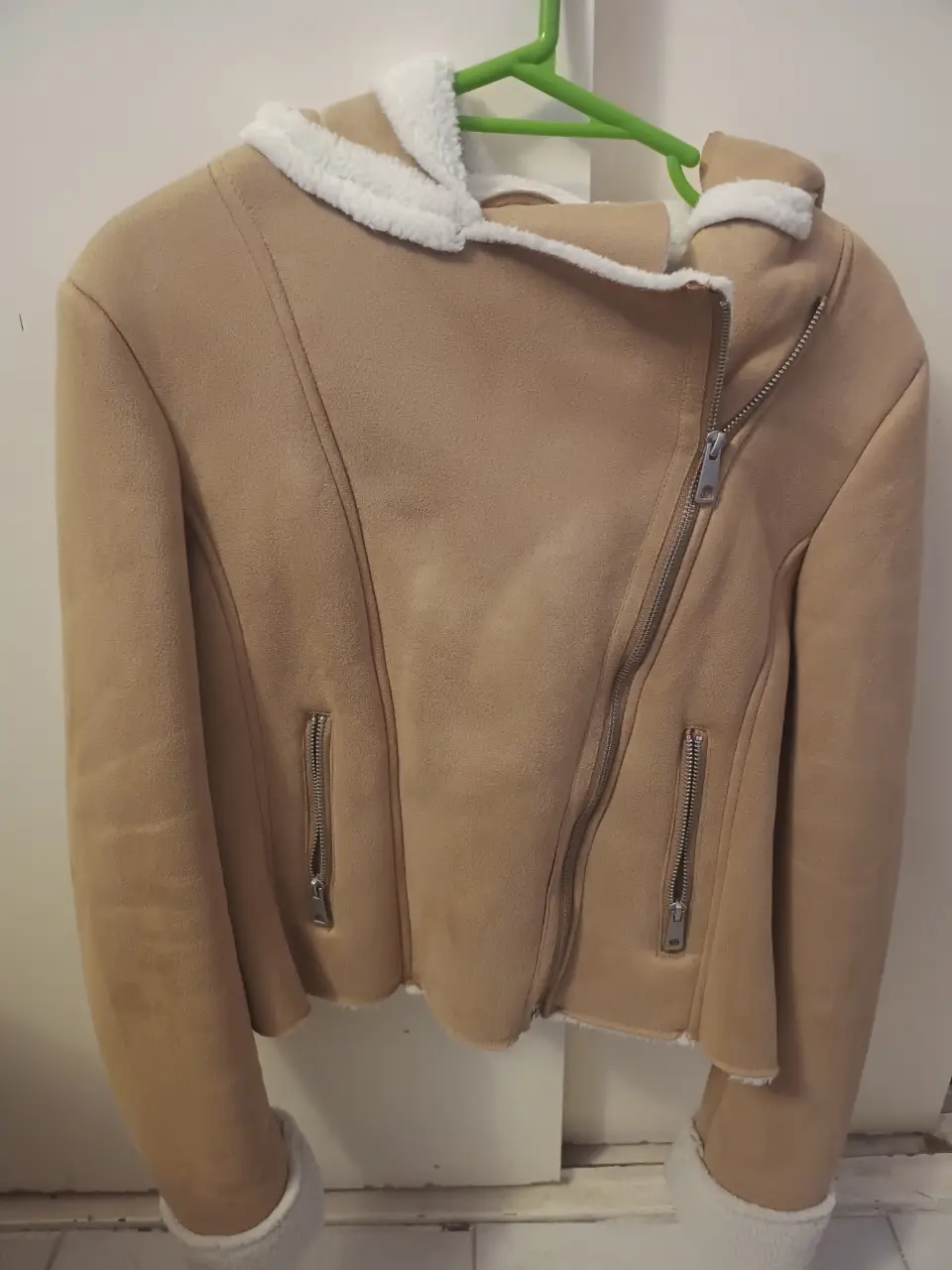 Campera de gamuza sintética color marrón claro con detalles en blanco en el cuello y puños. Posee cierre asimétrico y bolsillos con cierre. Muy poco uso.