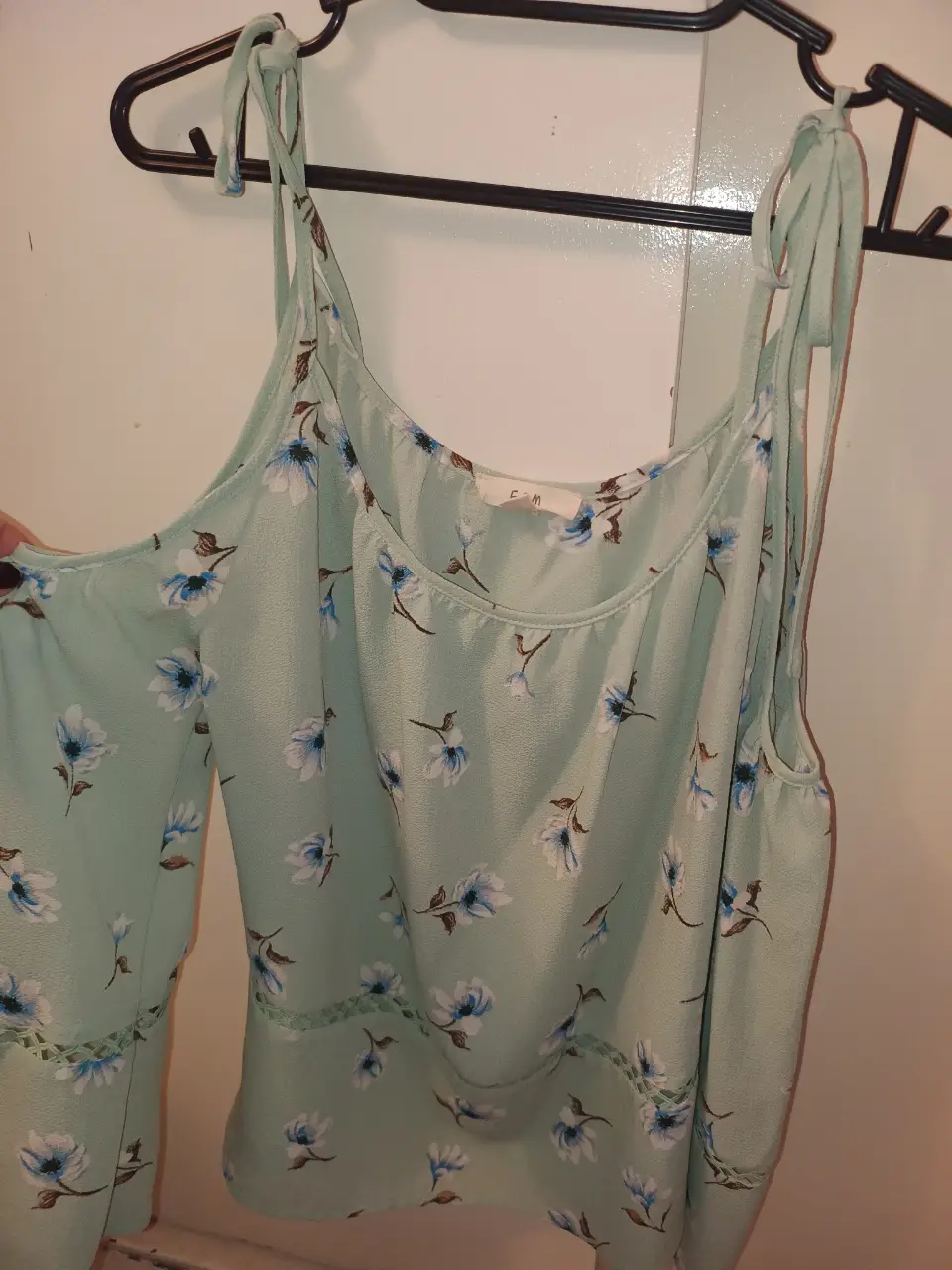 Blusa de mujer con estampado floral. Diseño con hombros descubiertos y mangas 3/4 con detalle de encaje. Color verde agua. 