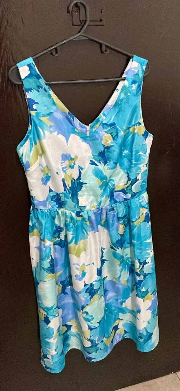 Vestido floreado en tonos azules y blancos, con escote en V y cierre en la espalda. Ideal para un look fresco y femenino.