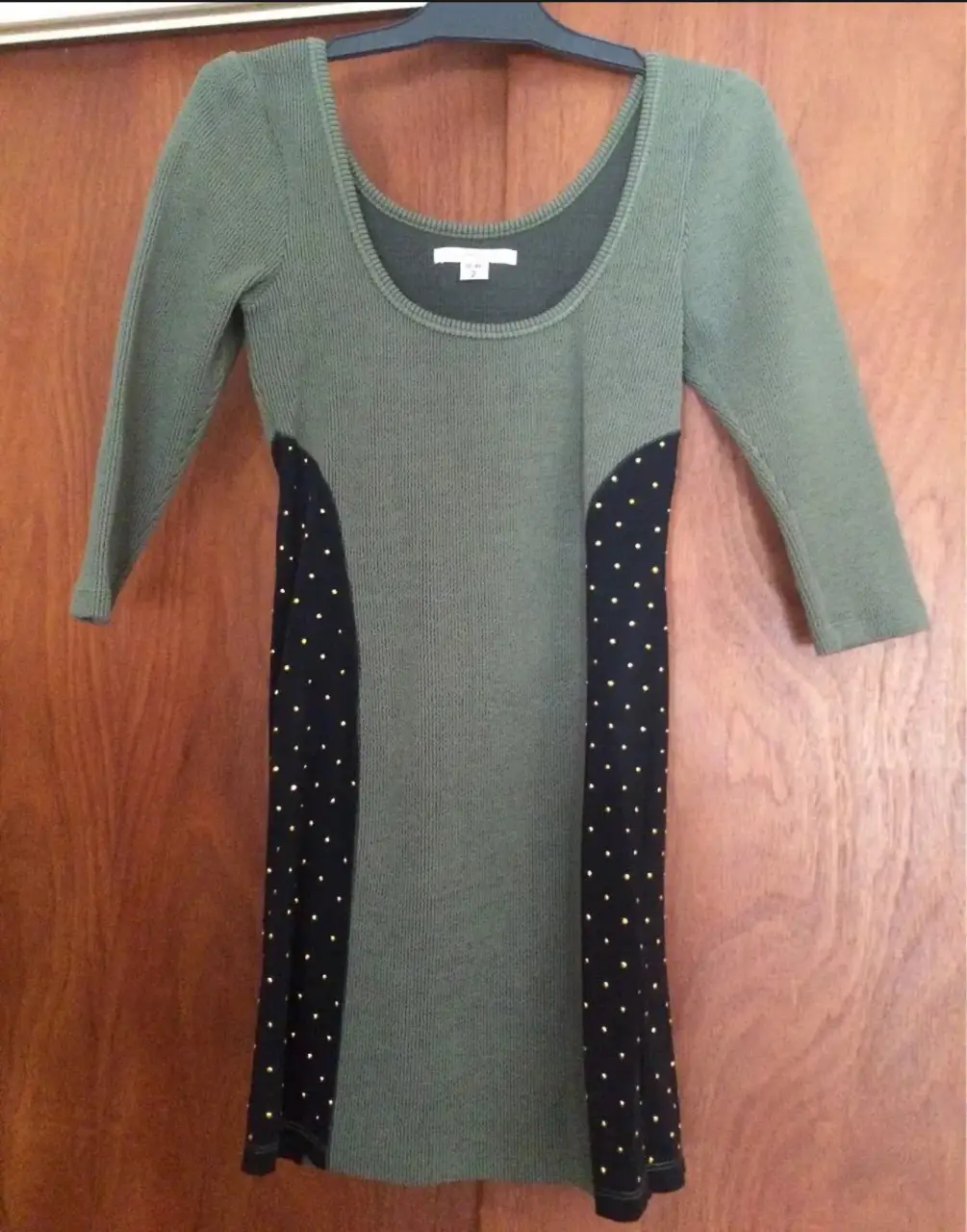 Vestido midi de punto en color verde oliva con paneles laterales negros con lunares dorados. Cuello redondo y mangas 3/4.
