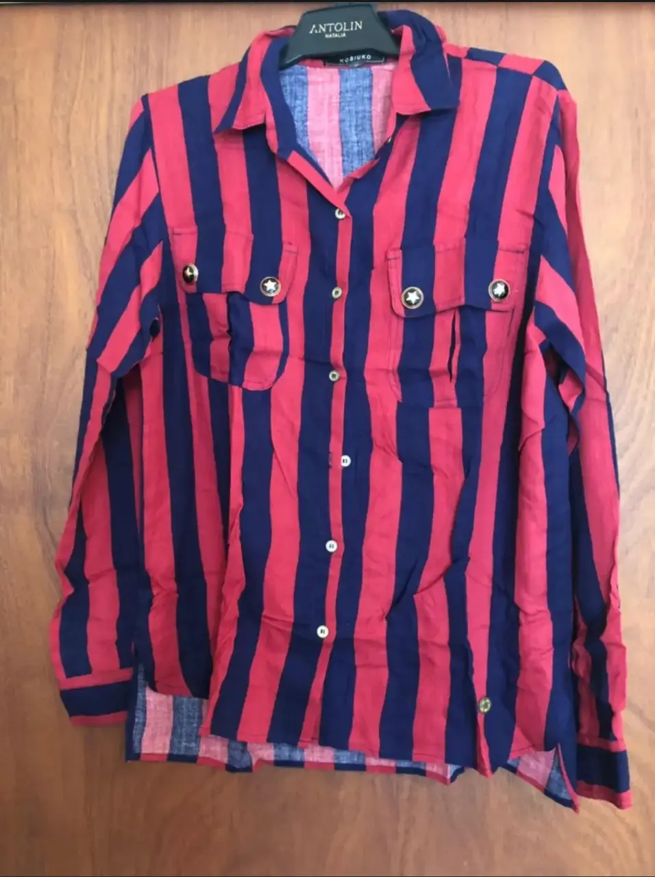 Camisa a rayas rojas y azules con botones dorados y bolsillos con detalles de estrellas. Ideal para un look casual con un toque vintage.