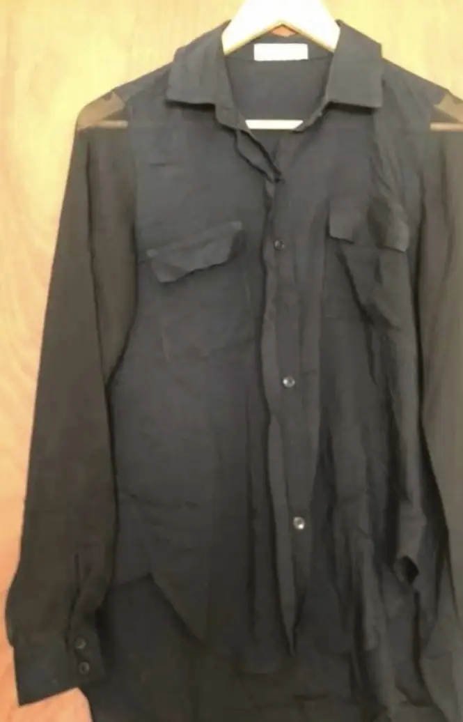 Camisa negra con mangas largas de gasa transparente y dos bolsillos delanteros. Ideal para un look elegante y sofisticado.