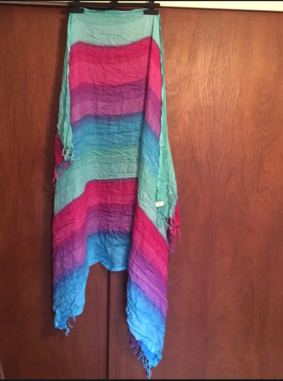 Pañuelo de tela con diseño a rayas en tonos azules, rosas y fucsias. Ideal para complementar cualquier look.