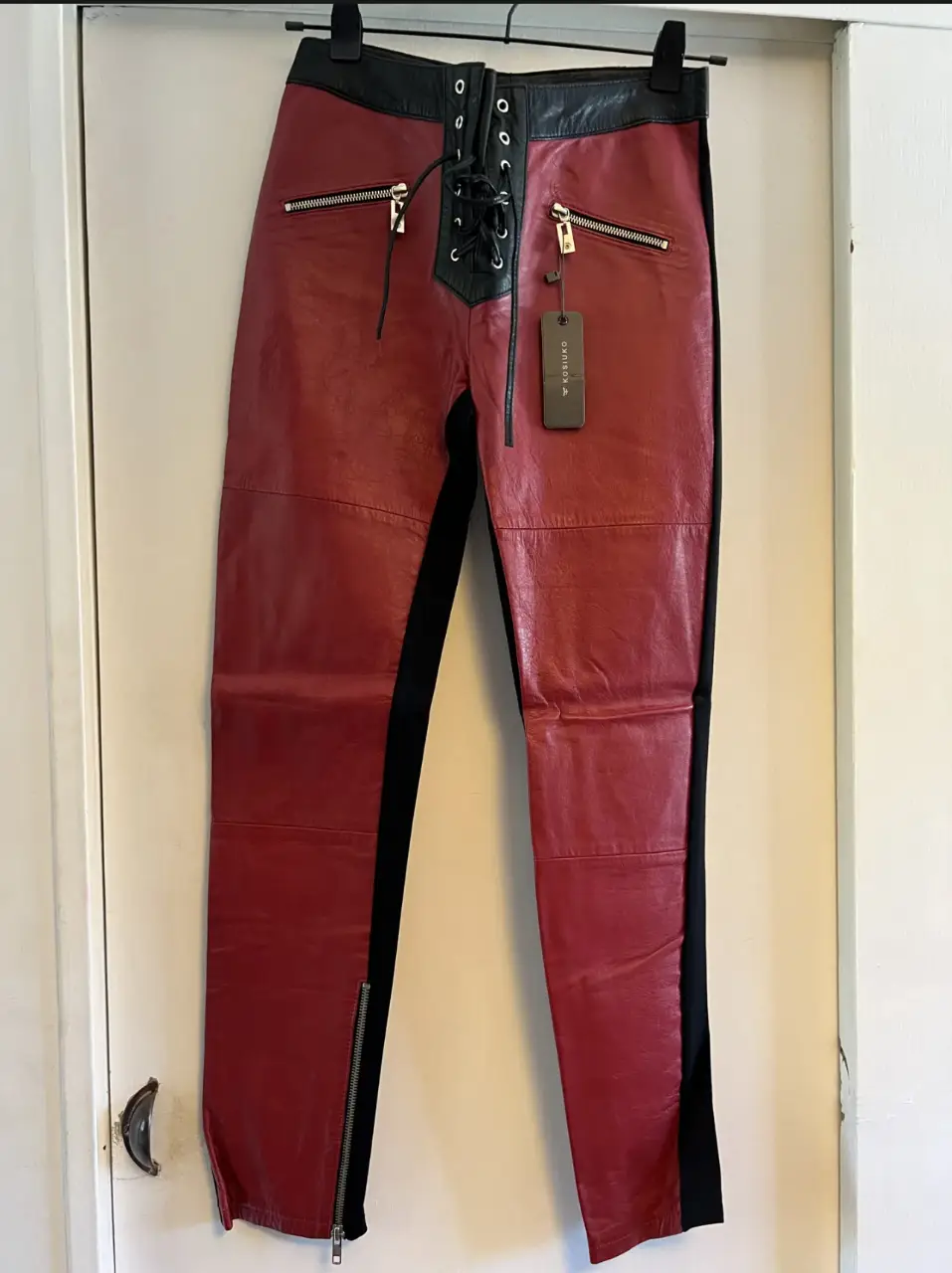 Pantalón de cuero rojo con detalles en negro y cierre en los tobillos. Estilo rocker y moderno, ideal para un look audaz.
