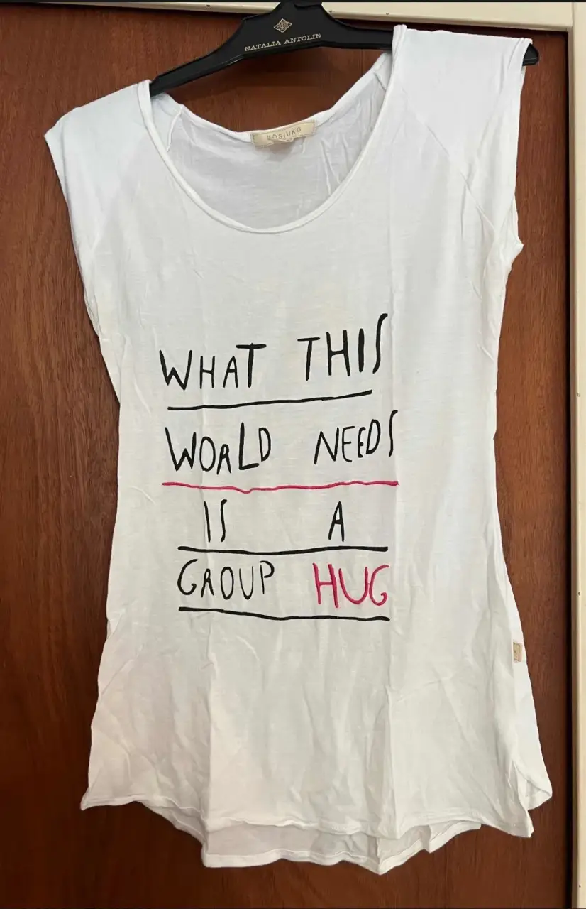 Remera blanca de algodón con estampado "WHAT THIS WORLD NEEDS IS A GROUP HUG". Ideal para un look casual y cómodo.