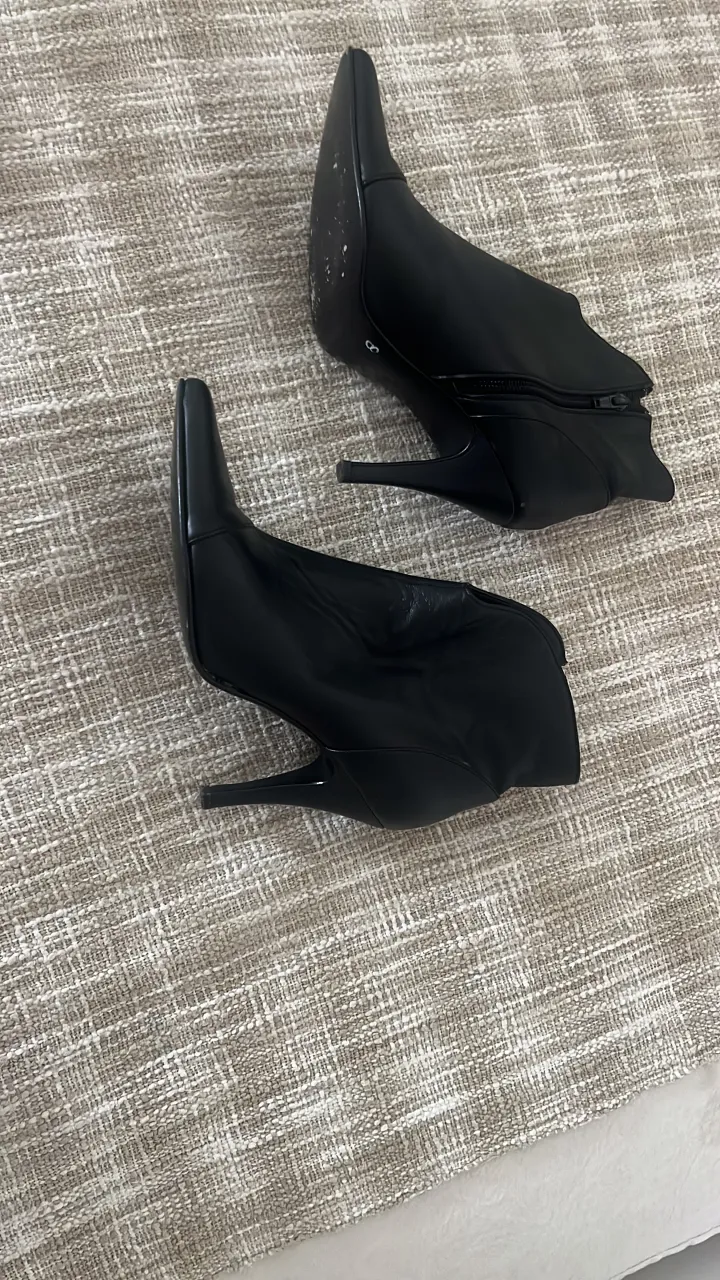 Botitas negras de taco alto con punta fina y cierre lateral.