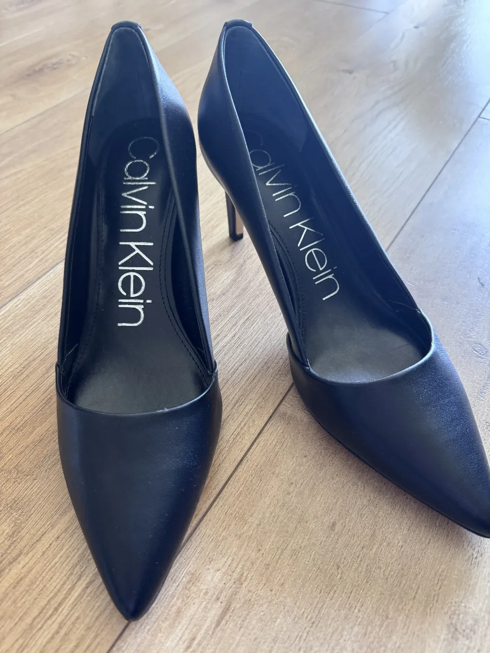 Elegantes zapatos de tacón Calvin Klein negros, ideales para eventos formales o salidas nocturnas. Sin uso.  Diseño clásico y sofisticado, perfectos para complementar cualquier atuendo.