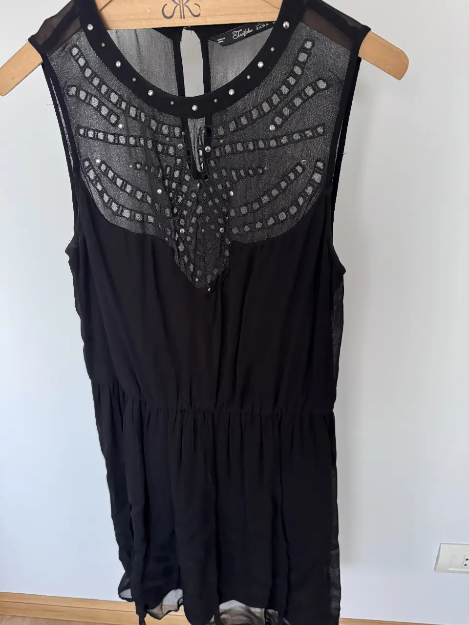 Vestido negro corto de Zara Trafaluc, con detalles de encaje y tachas pequeñas en la parte superior. Tela transparente y viso interior. Ideal para una salida o fiesta.
