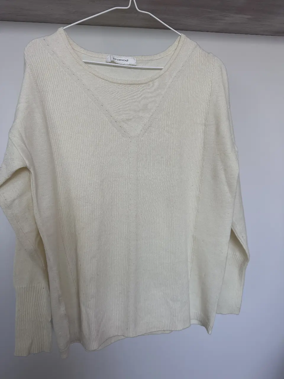 Sweater de mujer color crudo, con cuello en V y detalles acanalados. Puños anchos e hilos dorados. Ideal para un look casual y cómodo.