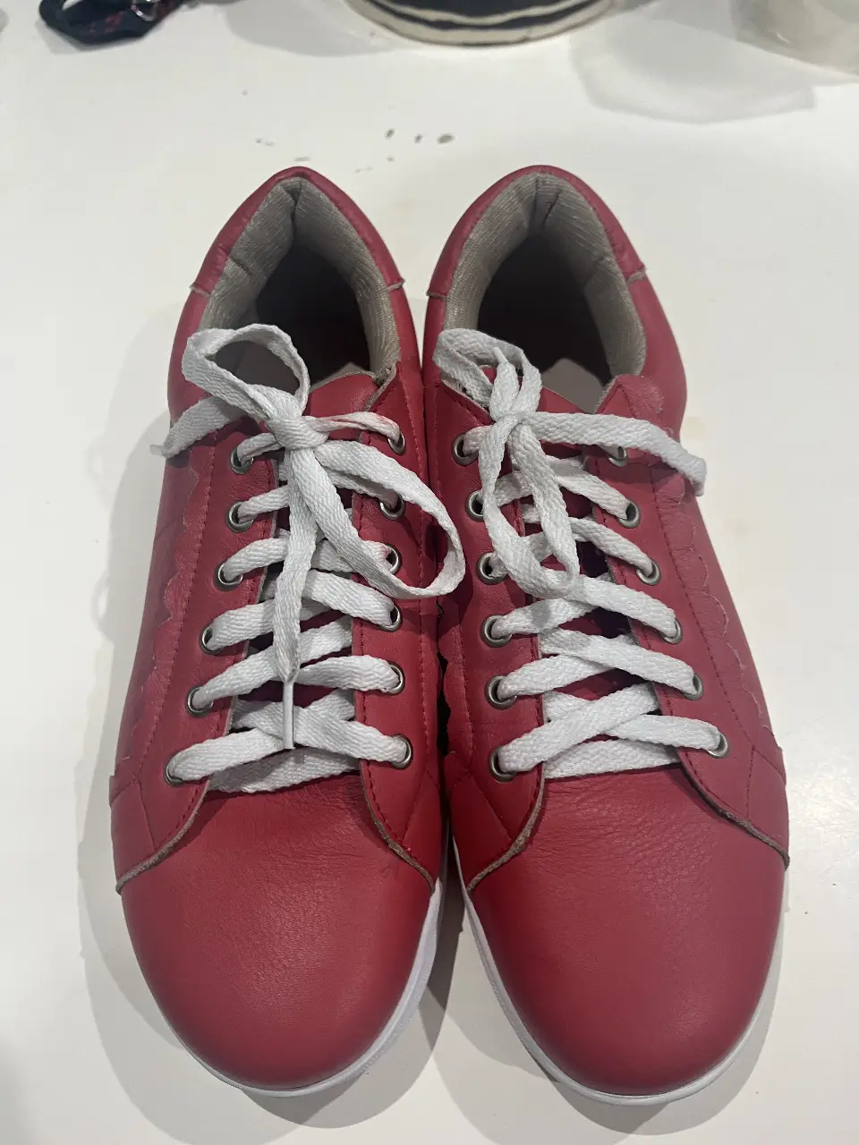 Zapatillas rojas de ecocuero con cordones blancos. Ideales para un look casual y cómodo.