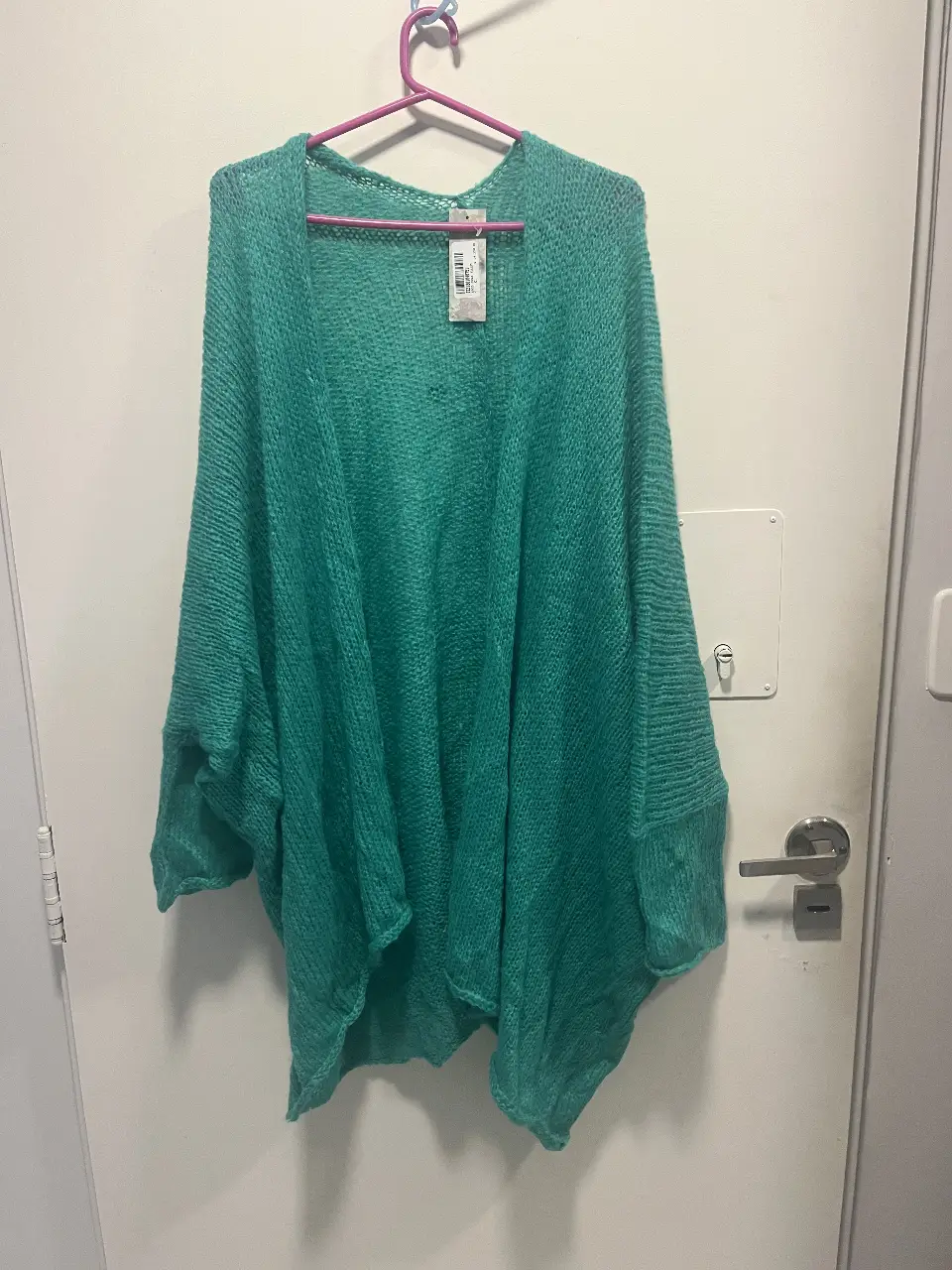 Cardigan tejido de color verde turquesa, con mangas amplias y corte holgado. Ideal para un look casual y cómodo.