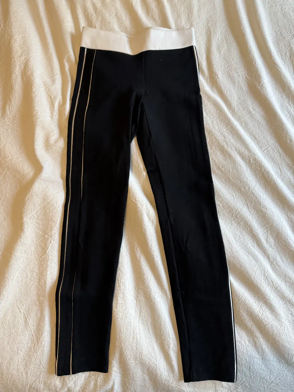 Calzas  negras con detalles blancos en los laterales y cintura. Ideal para un look casual y cómodo.