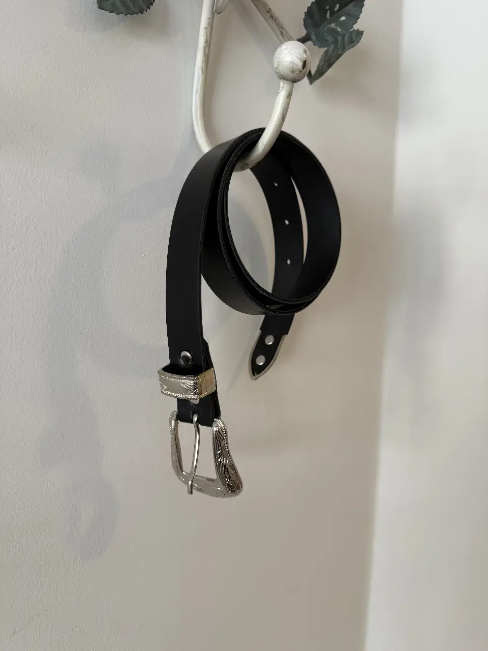 Cinturón de cuero negro con hebilla plateada con detalles. Ideal para completar cualquier look.