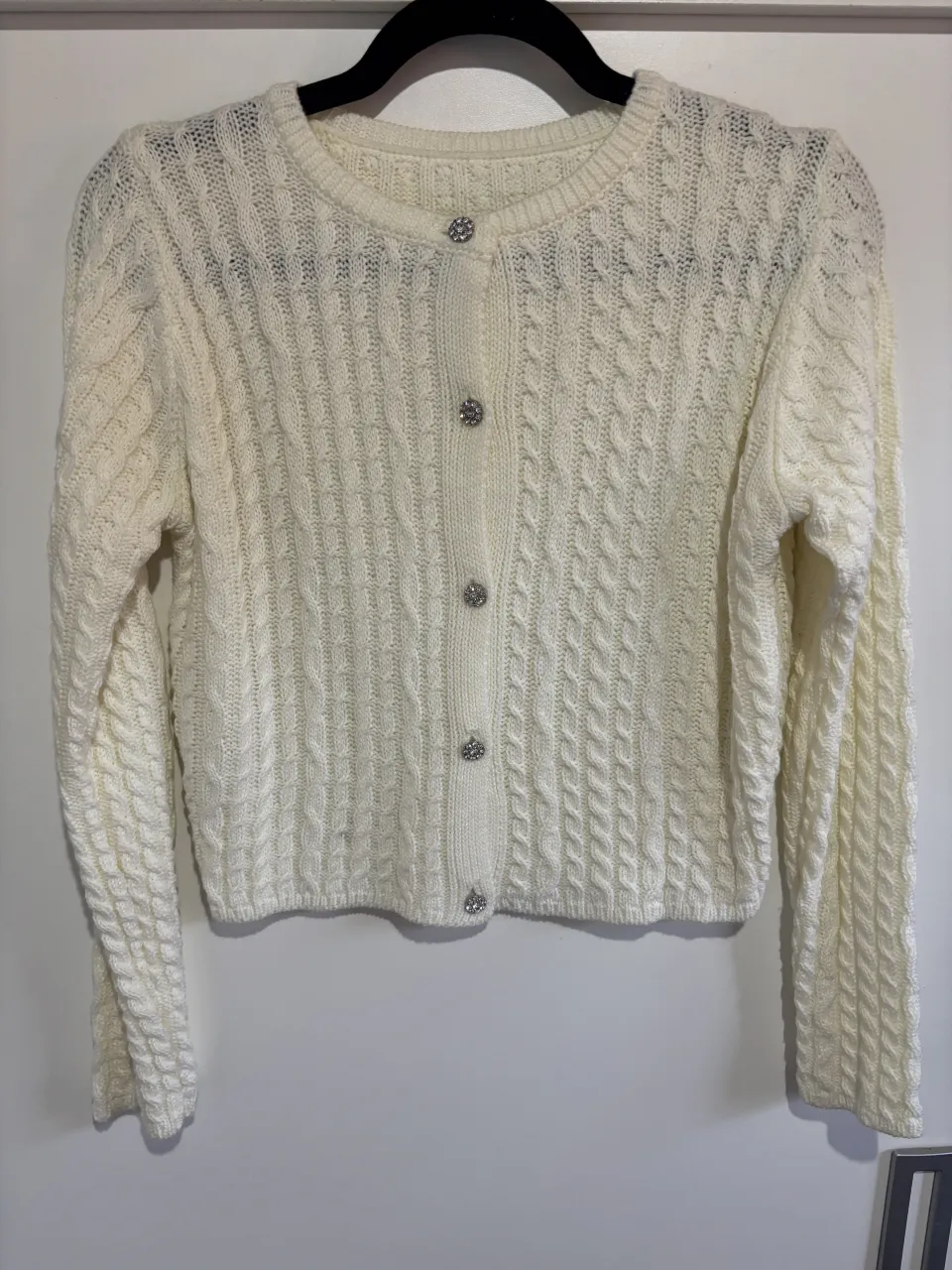 Cardigan tejido color crudo con botones brillantes. 