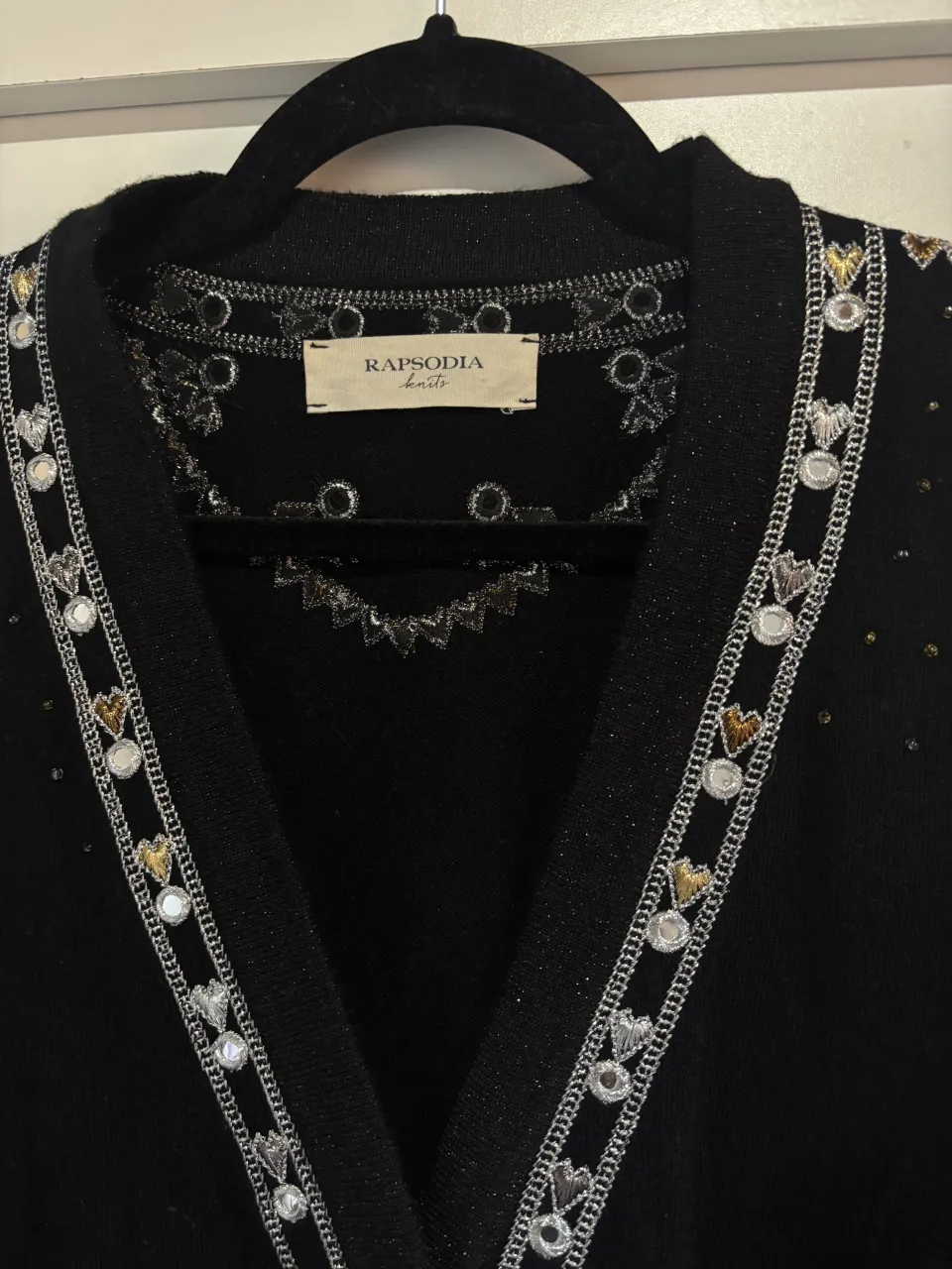 Cardigan negro con detalles bordados y brillos. Posee cuello en V, botones al frente y mangas largas con volados en los puños. Ideal para un look elegante y canchero.
Marca rapsodia, nueva 