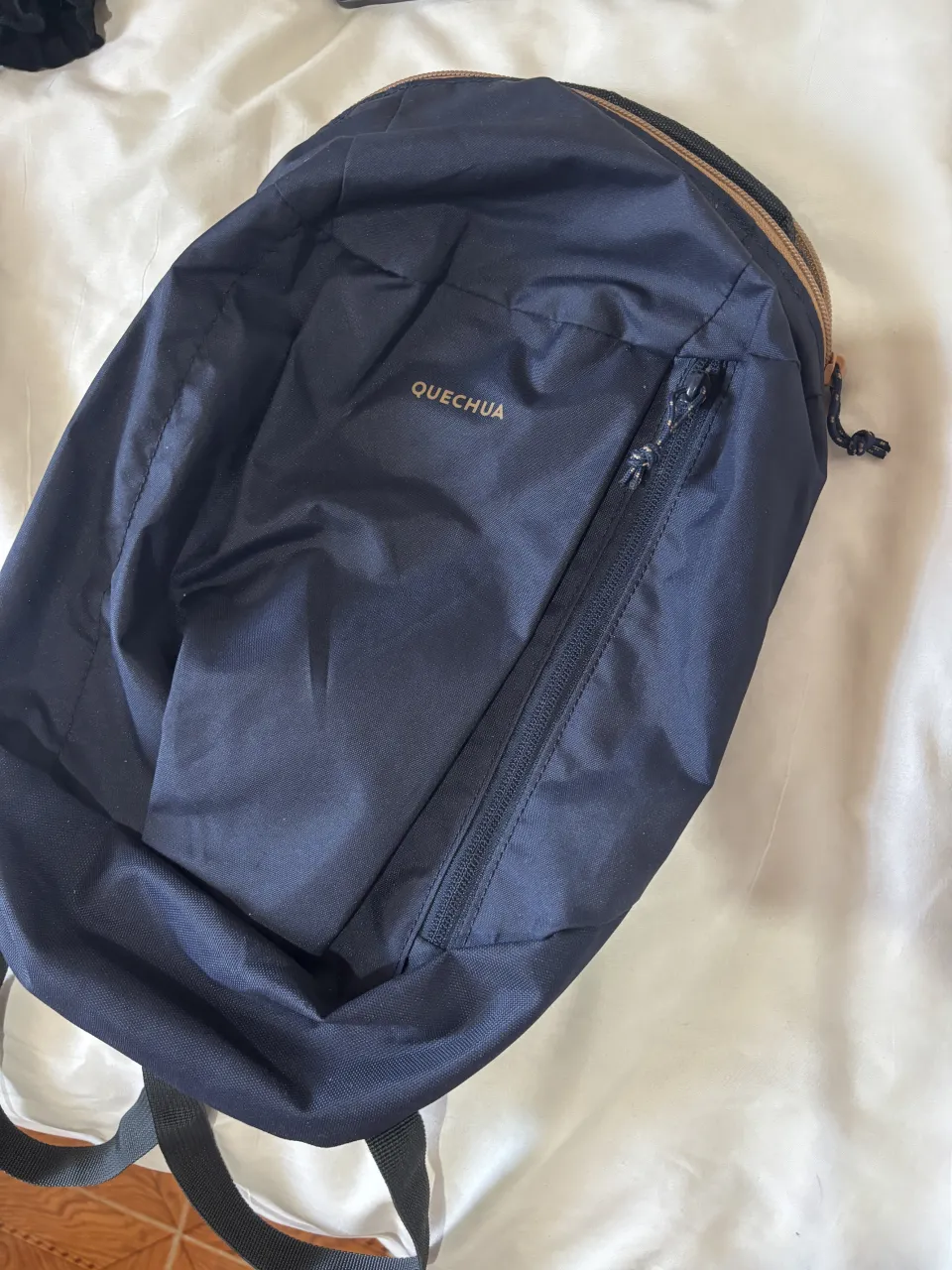 Mochila azul marino de la marca Quechua, ideal para actividades al aire libre o uso diario. Cuenta con un bolsillo frontal con cierre y un compartimento principal espacioso. Perfecta para llevar tus esenciales con comodidad y estilo.