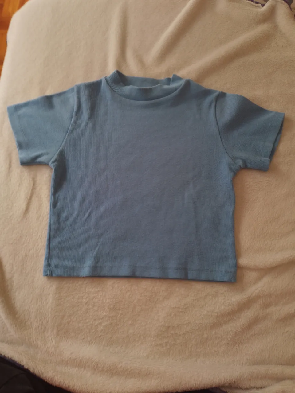 Remera azul de cuello redondo y mangas cortas, con un diseño acanalado. Perfecta para el día a día, súper cómoda y canchera.