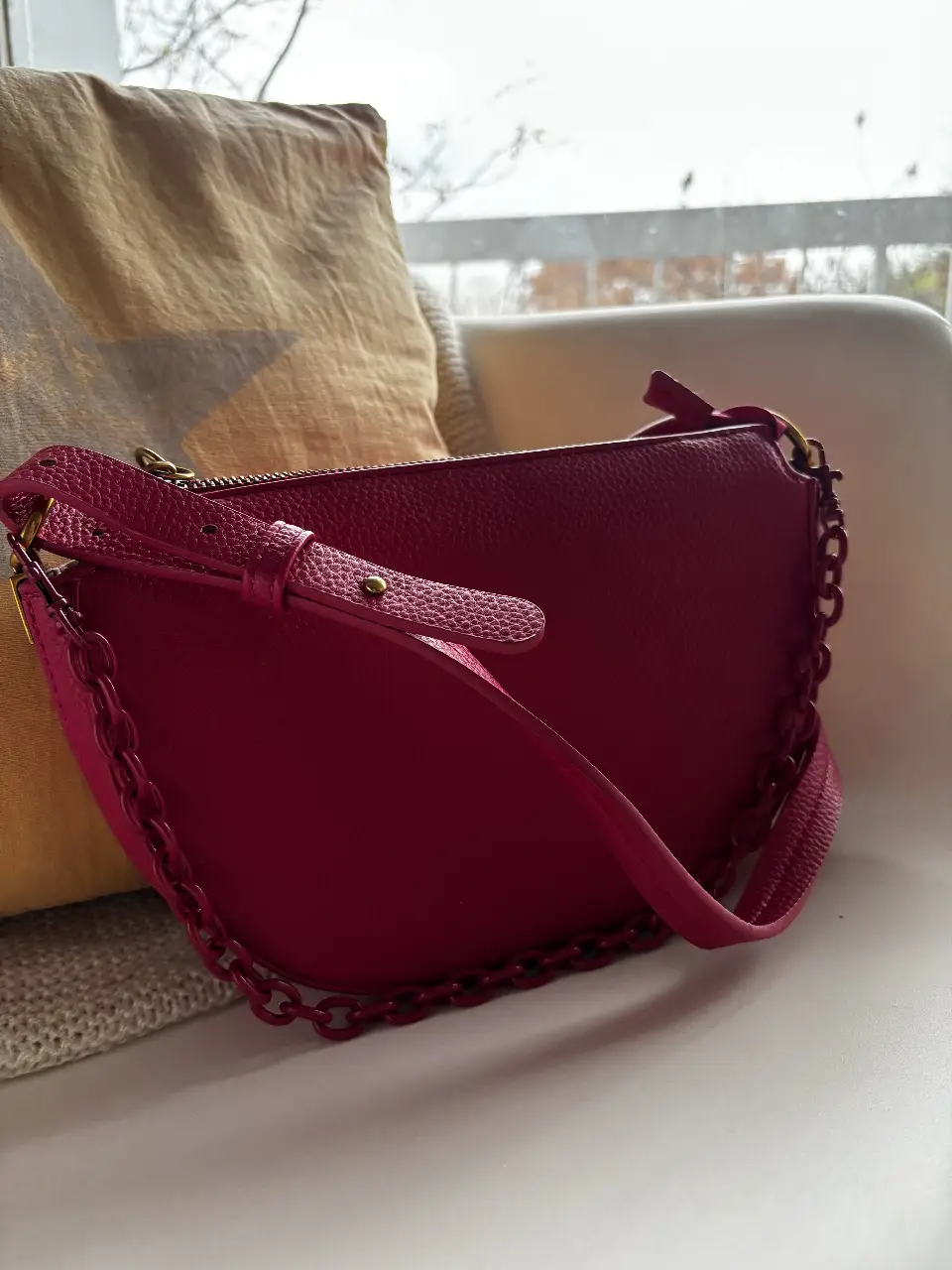 Cartera bandolera de cuero sintético color fucsia, con cadena y correa ajustable. Ideal para un look moderno y canchero.