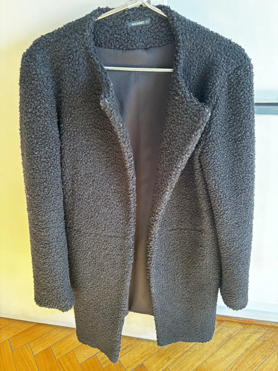 Tapado negro de textura bouclé, ideal para el invierno. Marca Bachino, talle L. Perfecto para un look elegante y abrigado.