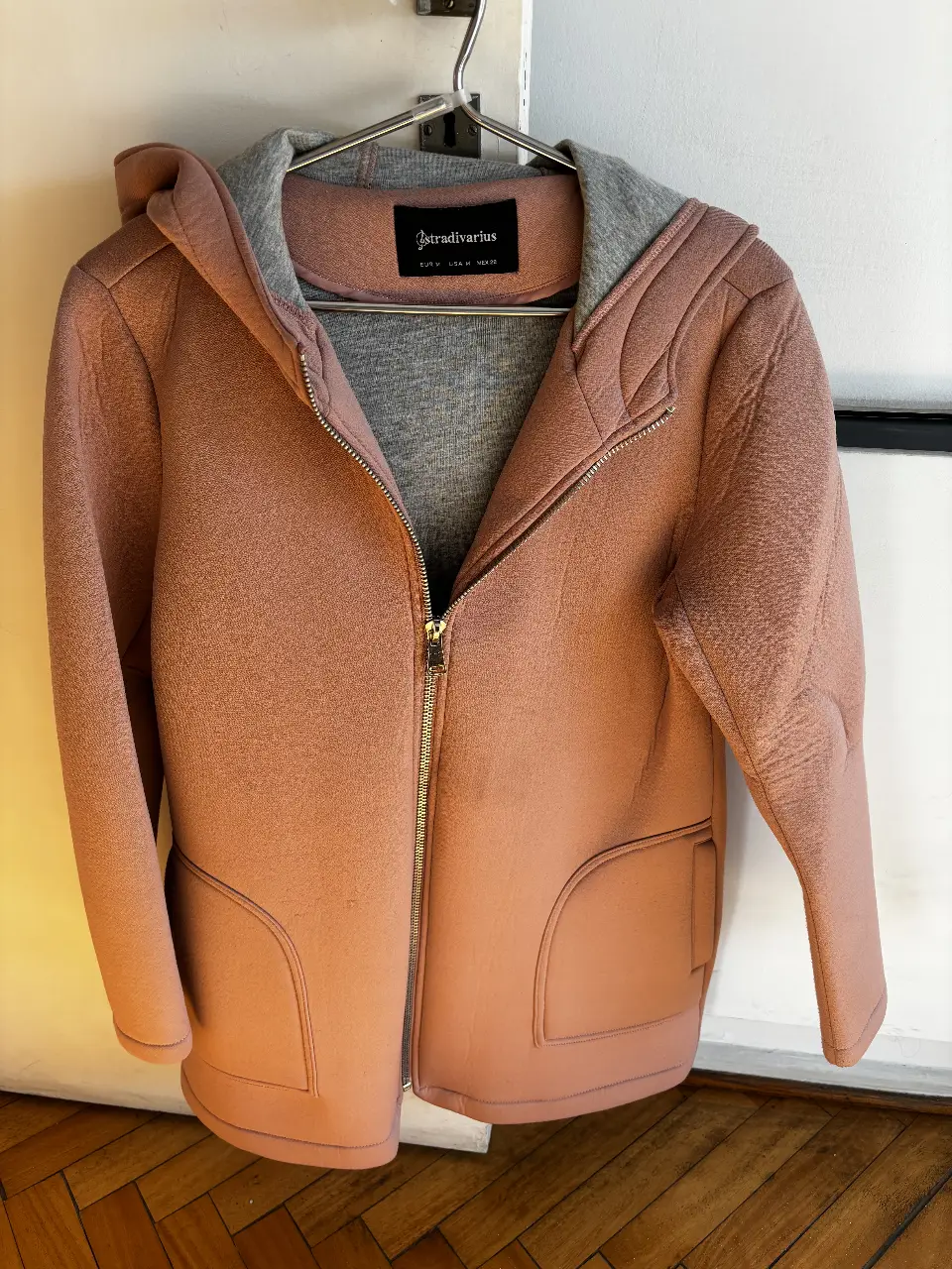 Campera con capucha de neoprene y algodón rosa, con cierre frontal y bolsillos. Ideal para un look casual y abrigado. Talle M.