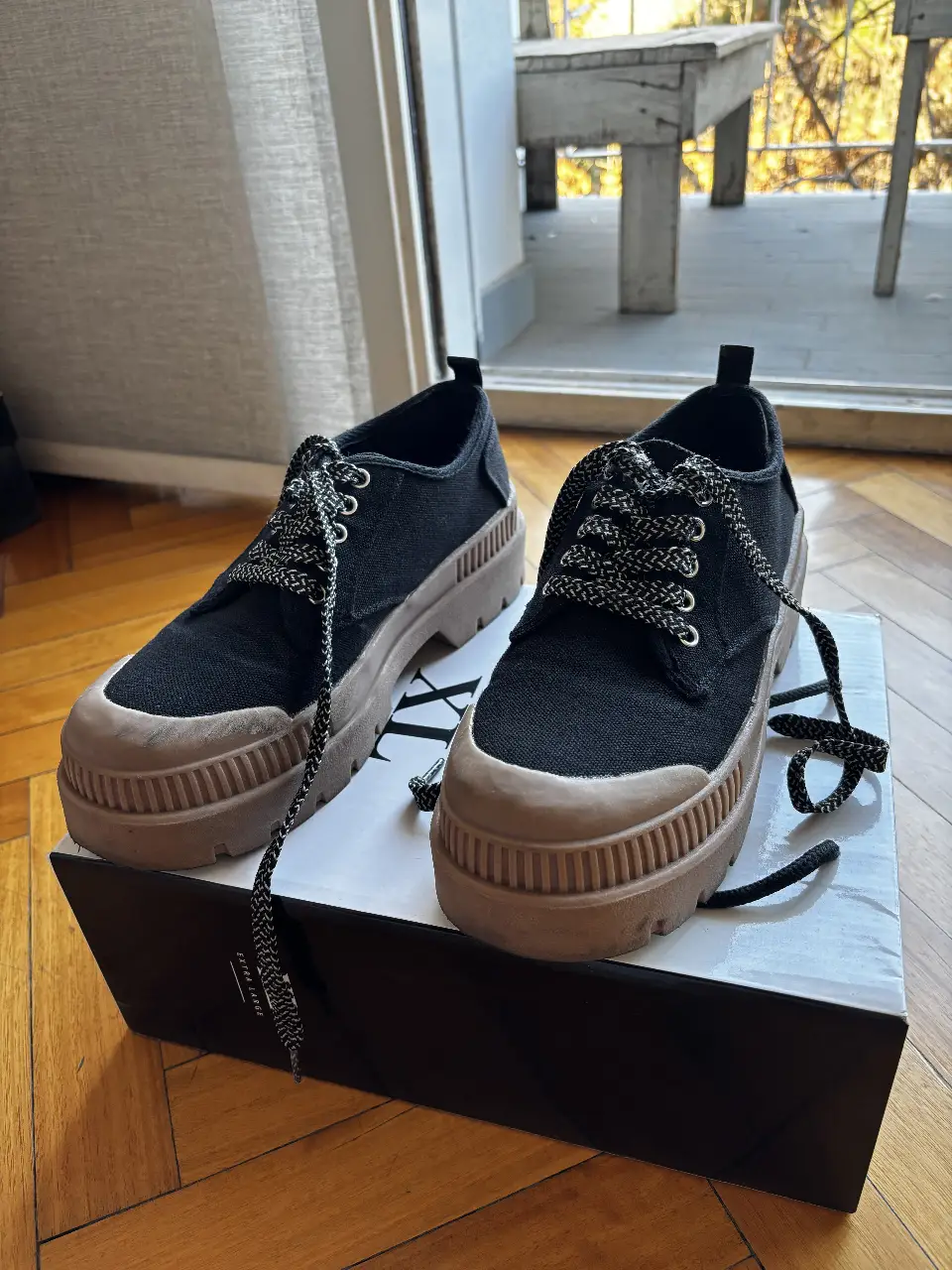 Zapatillas negras con suela marrón y cordones a tono. Diseño moderno y urbano, ideales para un look casual y cómodo.