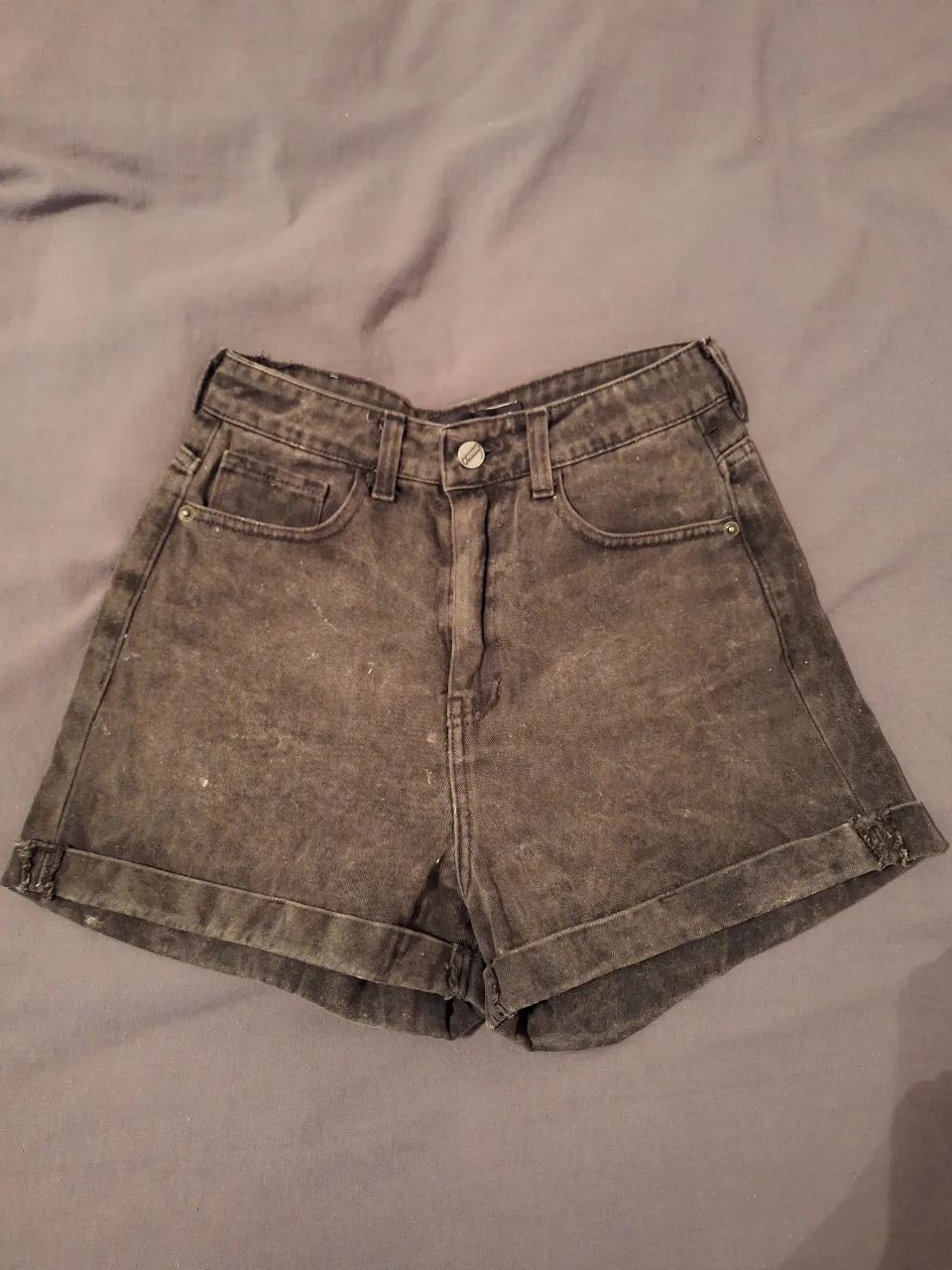 Shorts de jean tiro alto, color negro con efecto desgastado. Perfectos para un look casual y moderno.