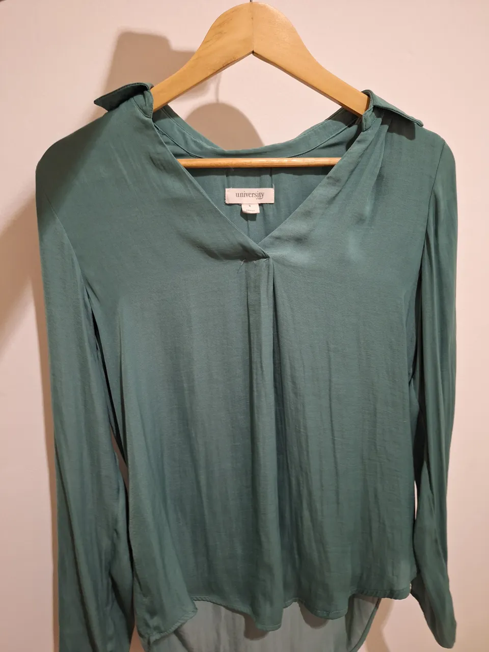 Camisa de vestir manga larga en color verde, con cuello, escote en V y detalles de pliegues en el frente. Perfecta para un look elegante y moderno.