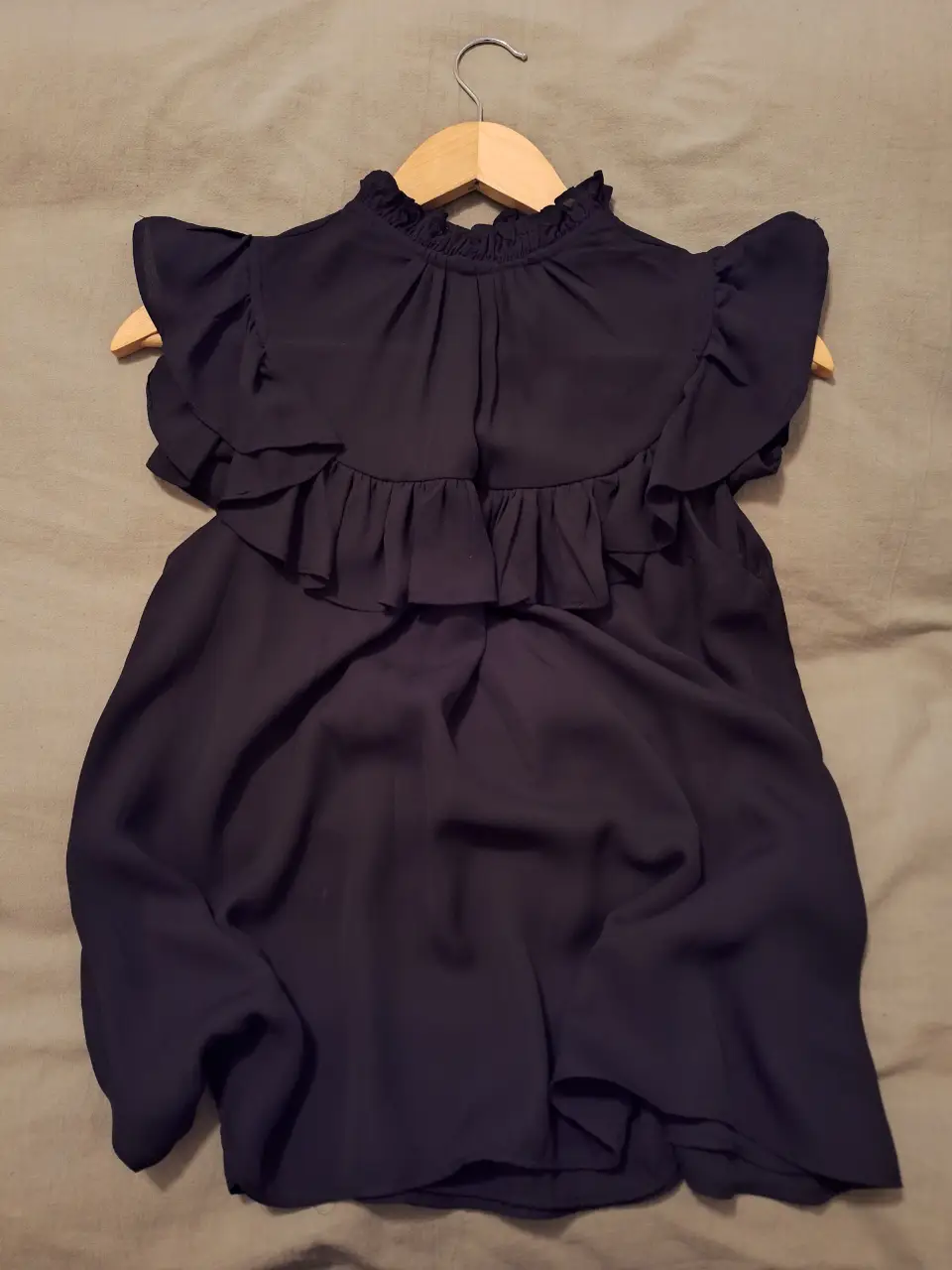 Blusa negra con volados en el cuello, musculosa. Ideal para un look elegante y sofisticado.