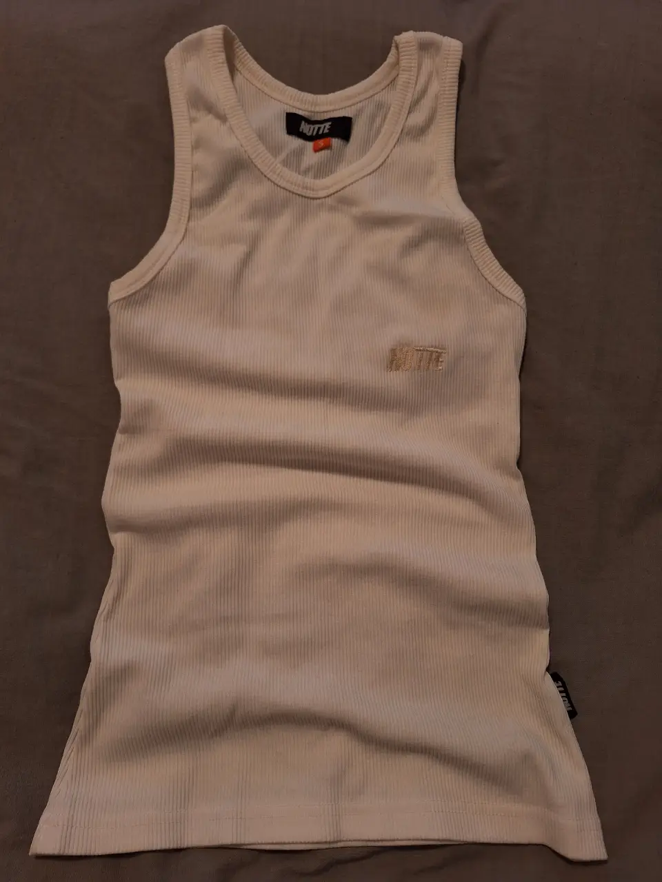 Musculosa de algodón acanalado color crudo, con detalle de logo bordado de la marca NOTTE CLOTHING. Ideal para un look casual y cómodo.