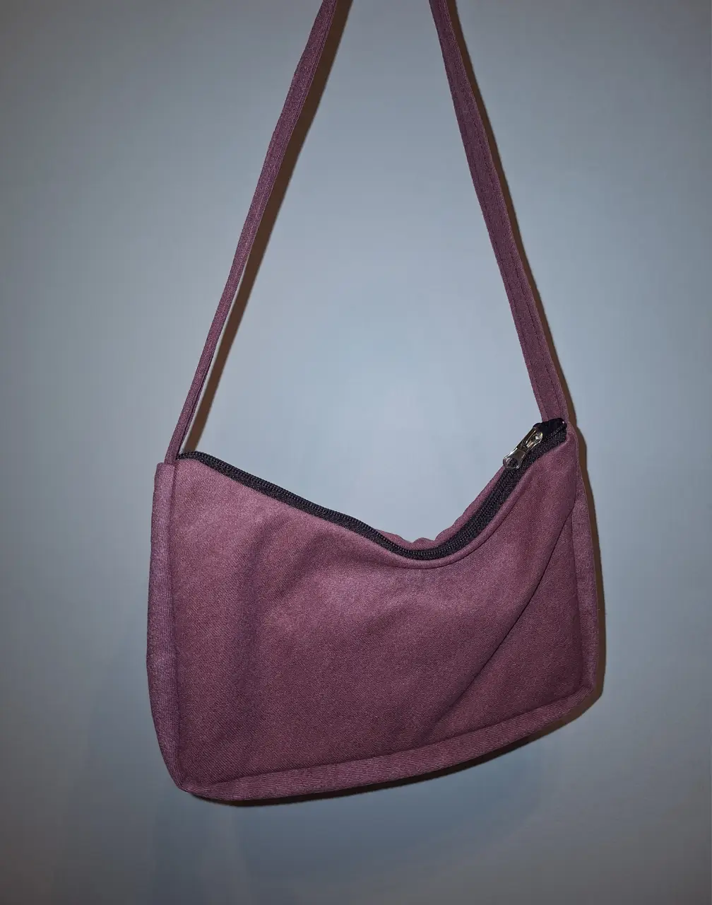 Cartera bandolera de tela rosa, ideal para llevar lo esencial con estilo. Cuenta con cierre y correa para colgar al hombro.