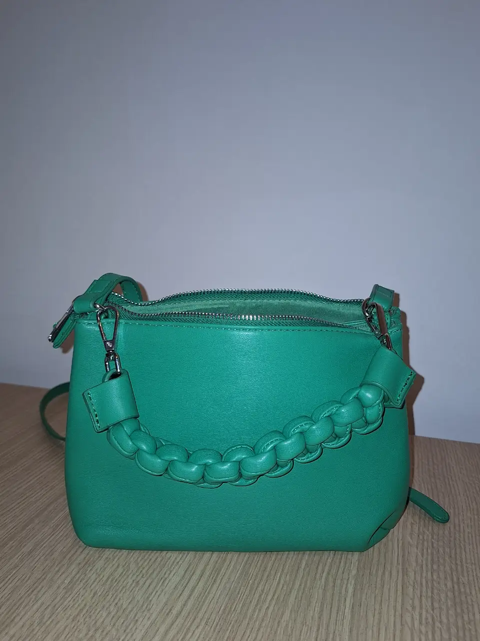Cartera bandolera verde con manija trenzada. Ideal para llevar tus esenciales con estilo y comodidad. Perfecta para un look casual y moderno.