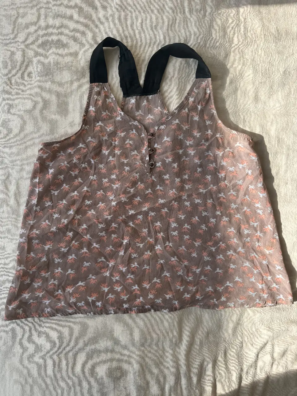 Blusa sin mangas con estampado de caballos en tonos marrones, blancos y rosados. Ideal para un look casual y fresco.