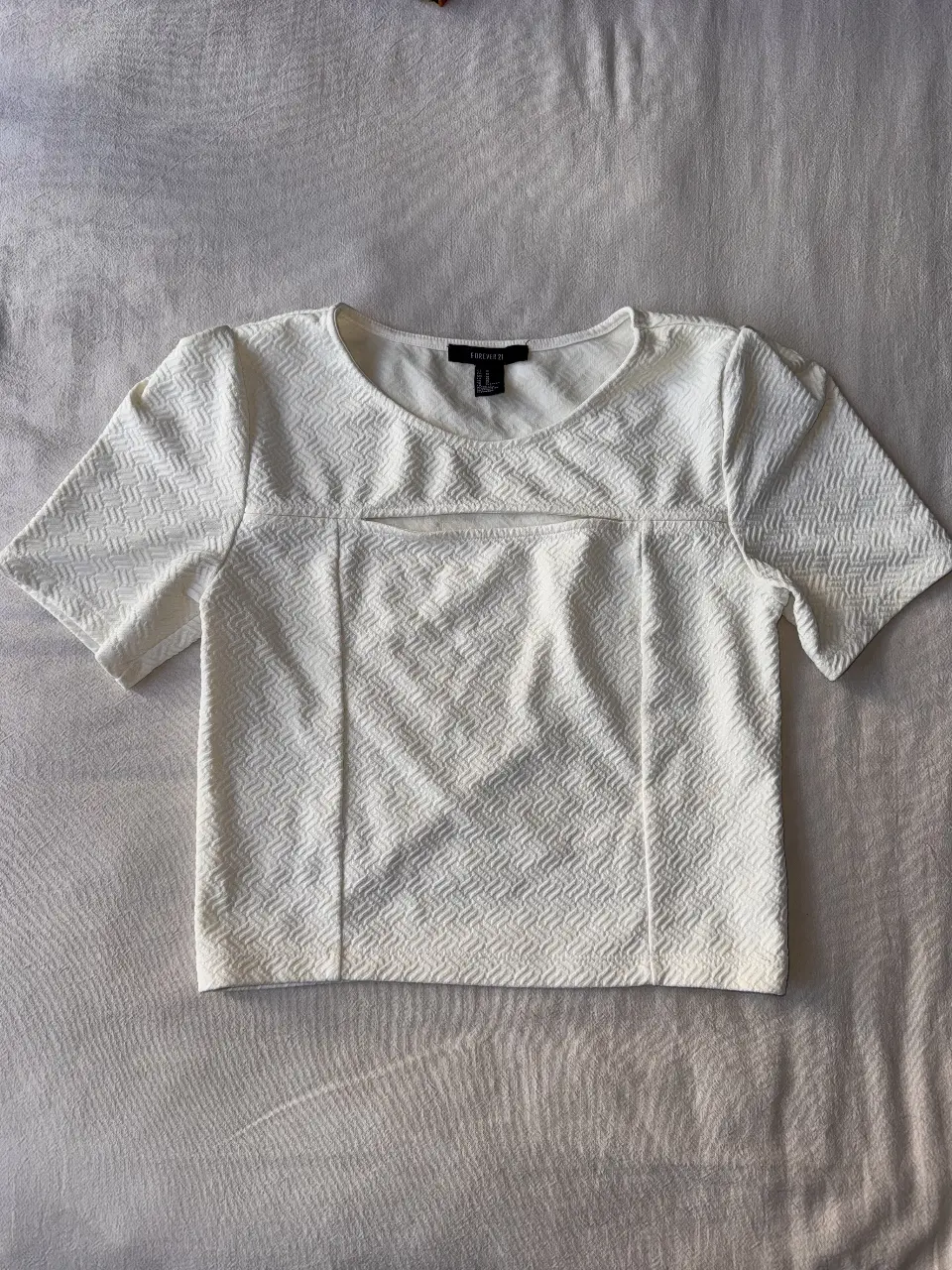 Blusa blanca de Forever 21, con detalle de abertura en el pecho y mangas cortas. Ideal para un look casual y moderno.
