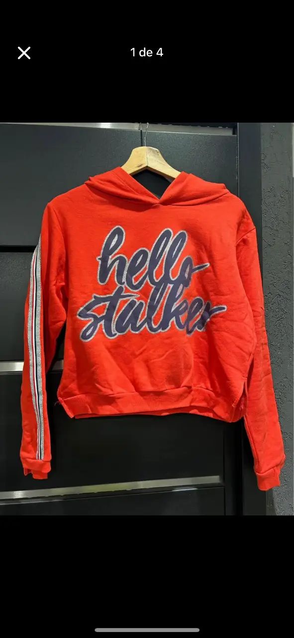 Buzo canguro rojo con estampado "hello stalker" en la parte delantera. Detalles de rayas en las mangas con un poco de glitter plateado. Ideal para un look casual y moderno.