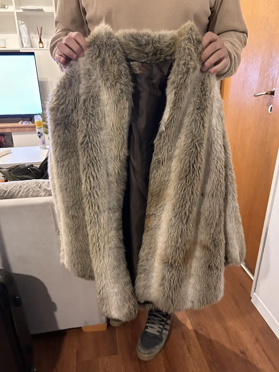 Tapado de piel sintética, largo y abrigado, ideal para el invierno. Confeccionado en un tono grisáceo con detalles marrones, perfecto para un look elegante y a la moda.