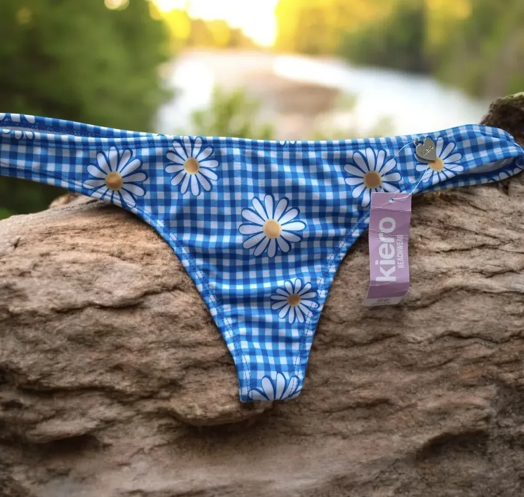 Bikini de dos piezas con un diseño alegre y veraniego. Presenta un estampado de cuadros azules con flores blancas, ideal para lucir en la playa o en la pileta. Su estilo es cómodo y fresco, perfecto para disfrutar del sol y el agua. Combina fácilmente con accesorios veraniegos y es una opción divertida para tus días de verano.