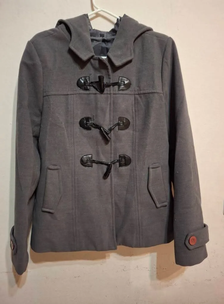 Campera gris con detalles de puños y botones. Posee capucha y cierre frontal.