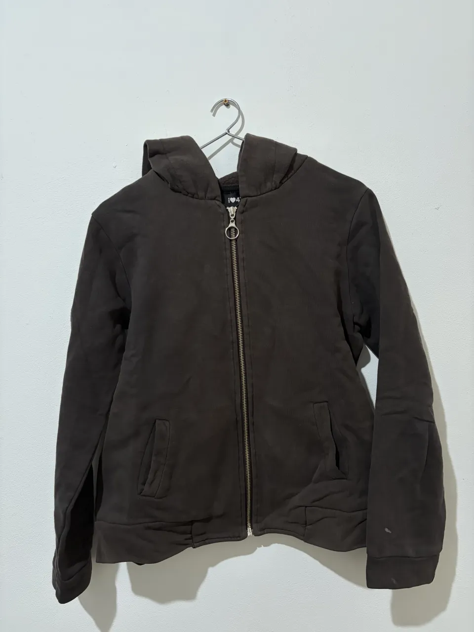 Campera con capucha y cierre completo, ideal para un look casual y cómodo. Perfecto para días frescos o para usar en casa. Tiene unas manchitas en uno de sus puños.