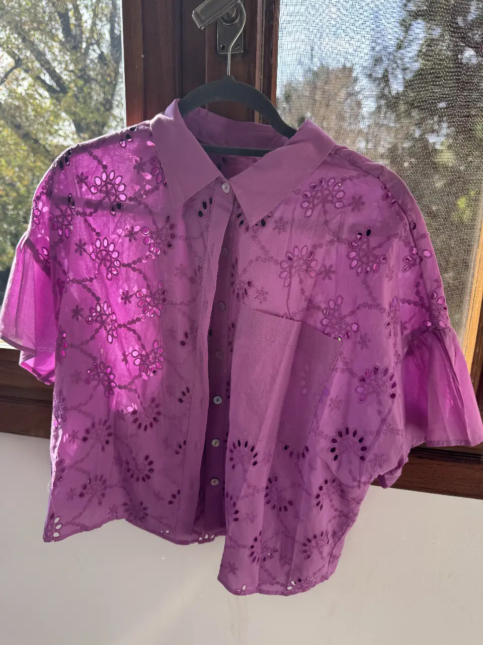Camisa de mujer color rosa con detalles calados y mangas cortas con volados. Ideal para un look fresco y femenino.