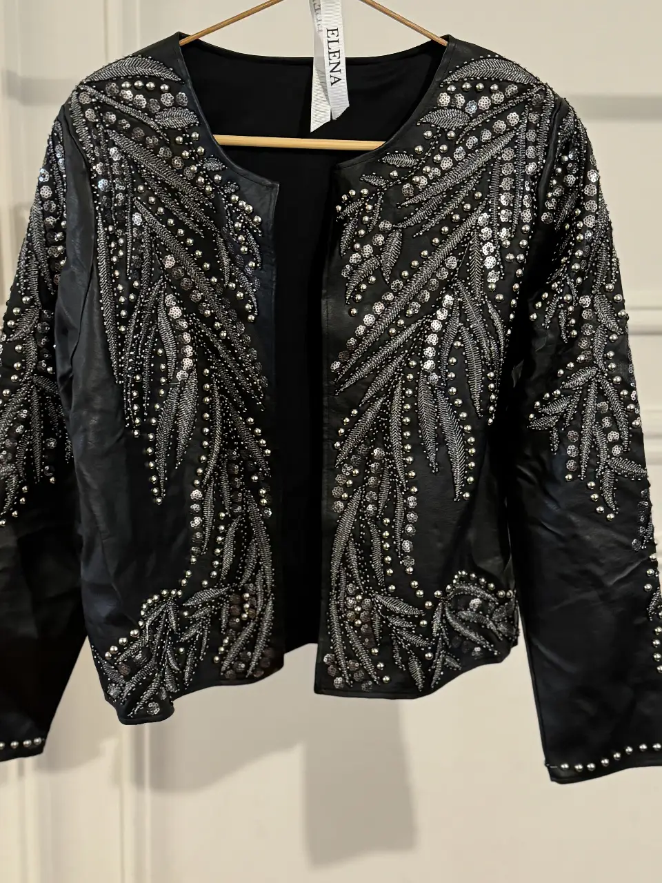 Campera de cuero negra con apliques plateados. Diseño con detalles de lentejuelas y canutillos en forma de hojas. Ideal para un look de fiesta o salida.