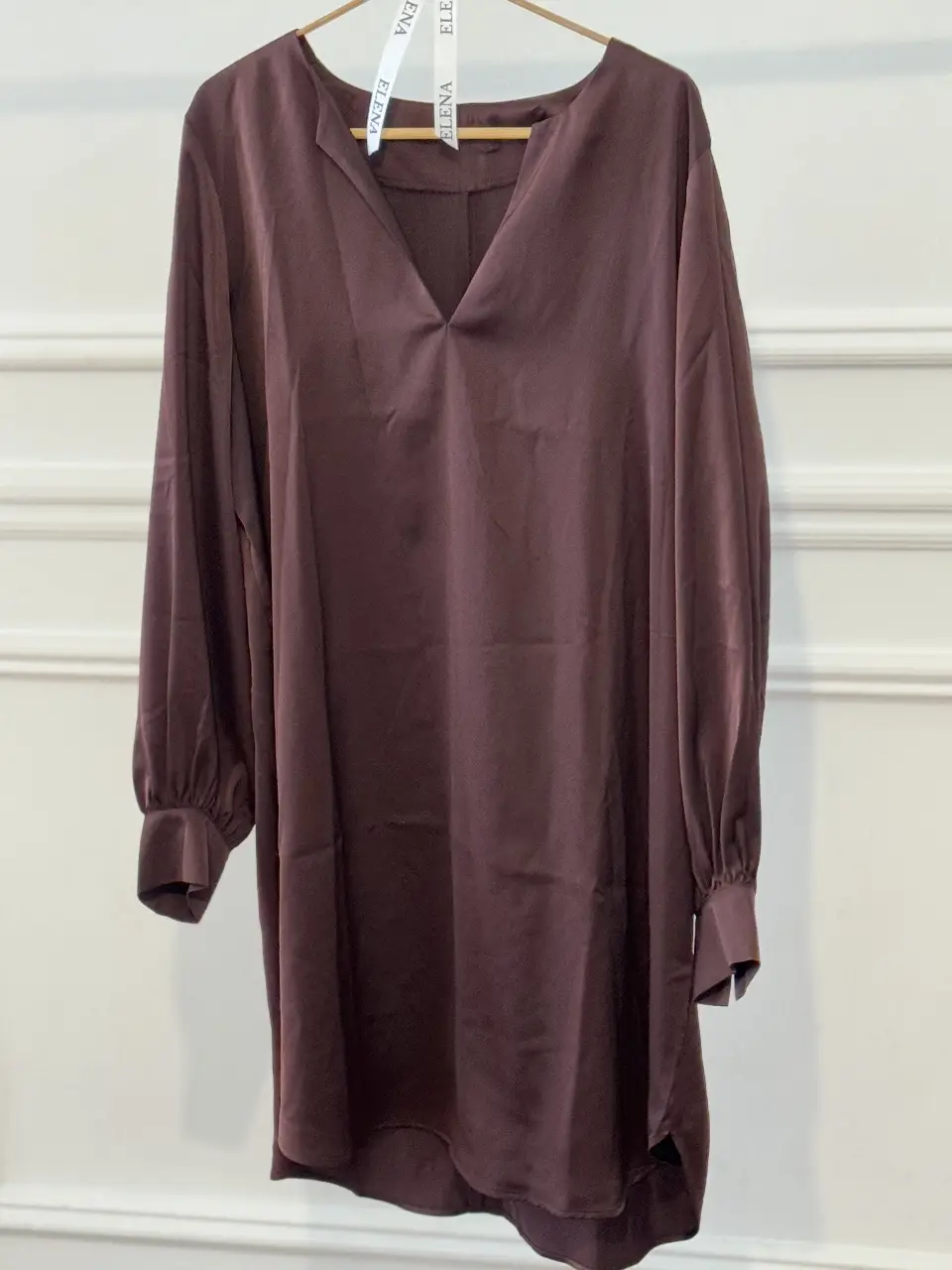 Vestido corto simil satén en color marrón/uva. Cuello en V y mangas largas con puños. Ideal para un look elegante y sofisticado.