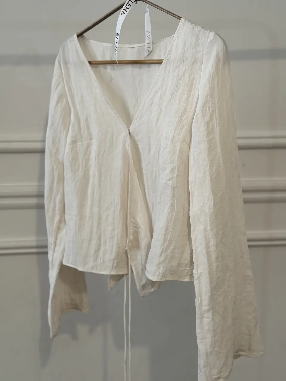 Blusa blanca de manga larga con escote en V y detalle de lazo. Ideal para un look elegante y sofisticado.