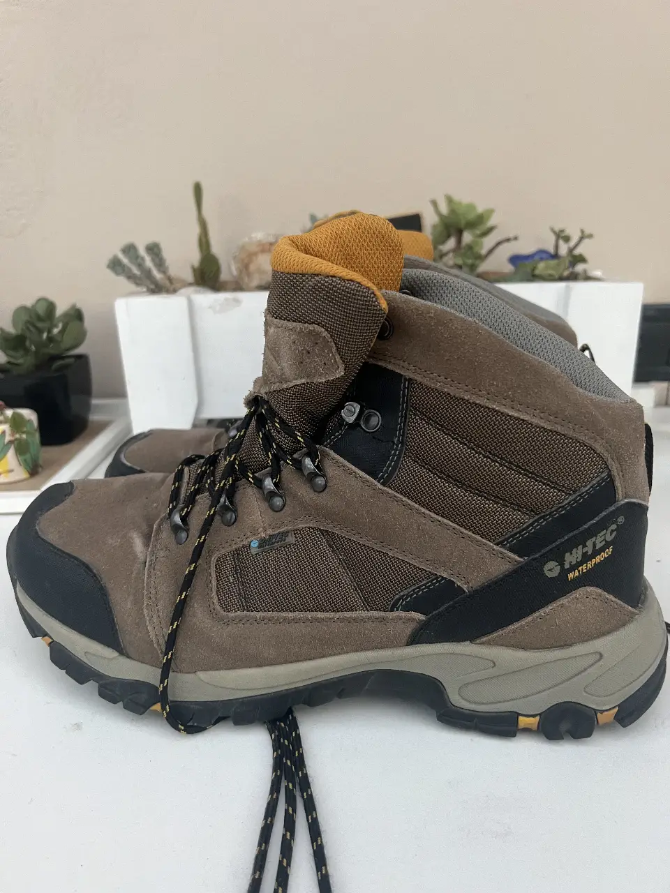 Borcegos Hi-Tec impermeables para hombre, color marrón con detalles en negro y amarillo. Ideales para trekking y actividades al aire libre.